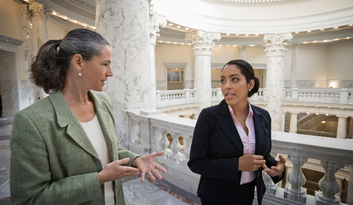 Two women walking while talking in a government building